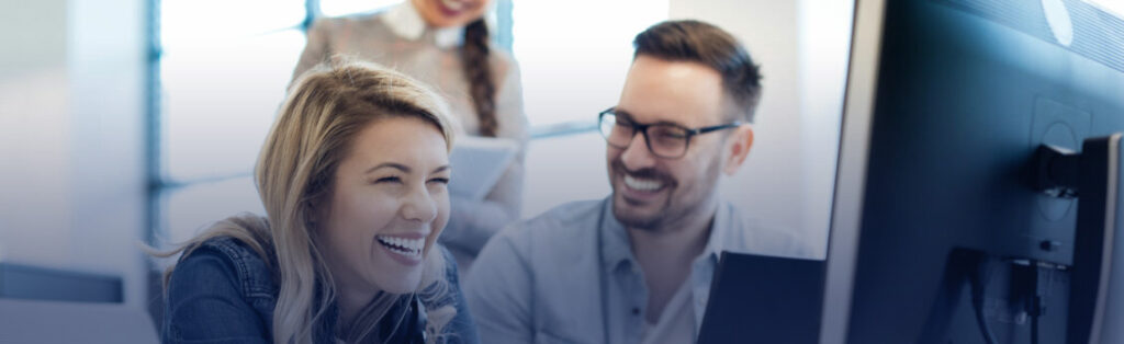 Happy team laughing at a computer in an office